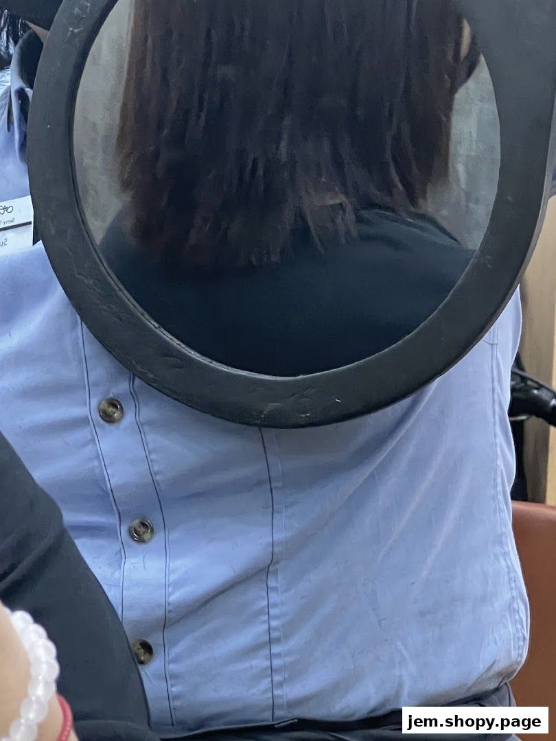 A person wearing a light blue shirt is reflected in a circular mirror.