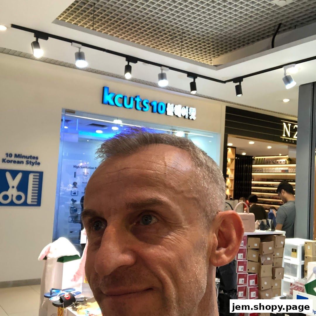 A man poses in front of a hair salon called 'kcuts10' offering Korean style haircuts.