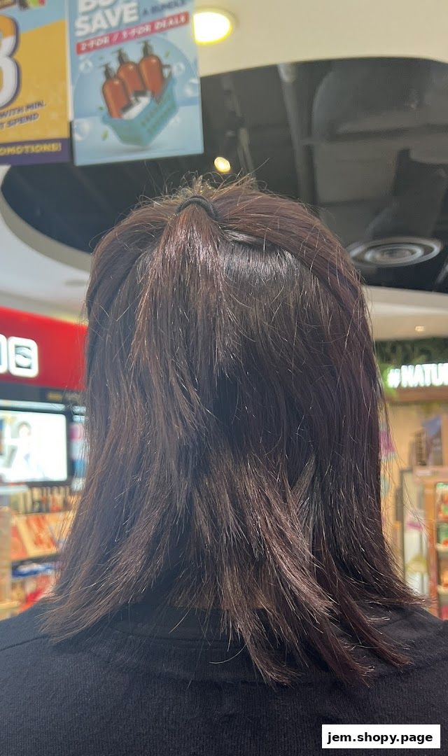 Back view of a person with dark hair, with shop promotions visible in the background.