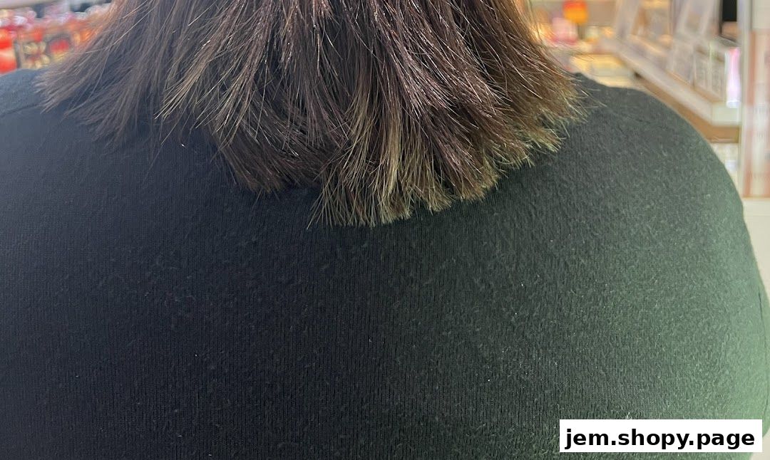 Close-up of a person's dark hair with lighter ends, against a dark green shirt.