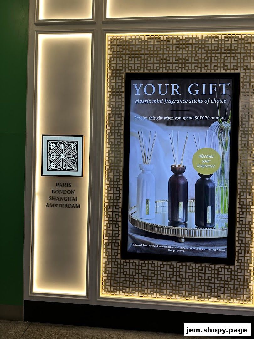 A digital display advertises a gift of mini fragrance sticks with a minimum spend.