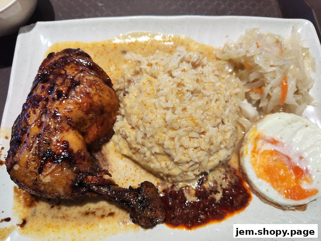 A plate of Indonesian BBQ chicken with rice, coleslaw, and a fried egg.