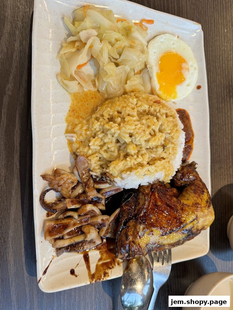 A plate of Indonesian BBQ with rice, grilled squid, chicken, fried egg, and salad.