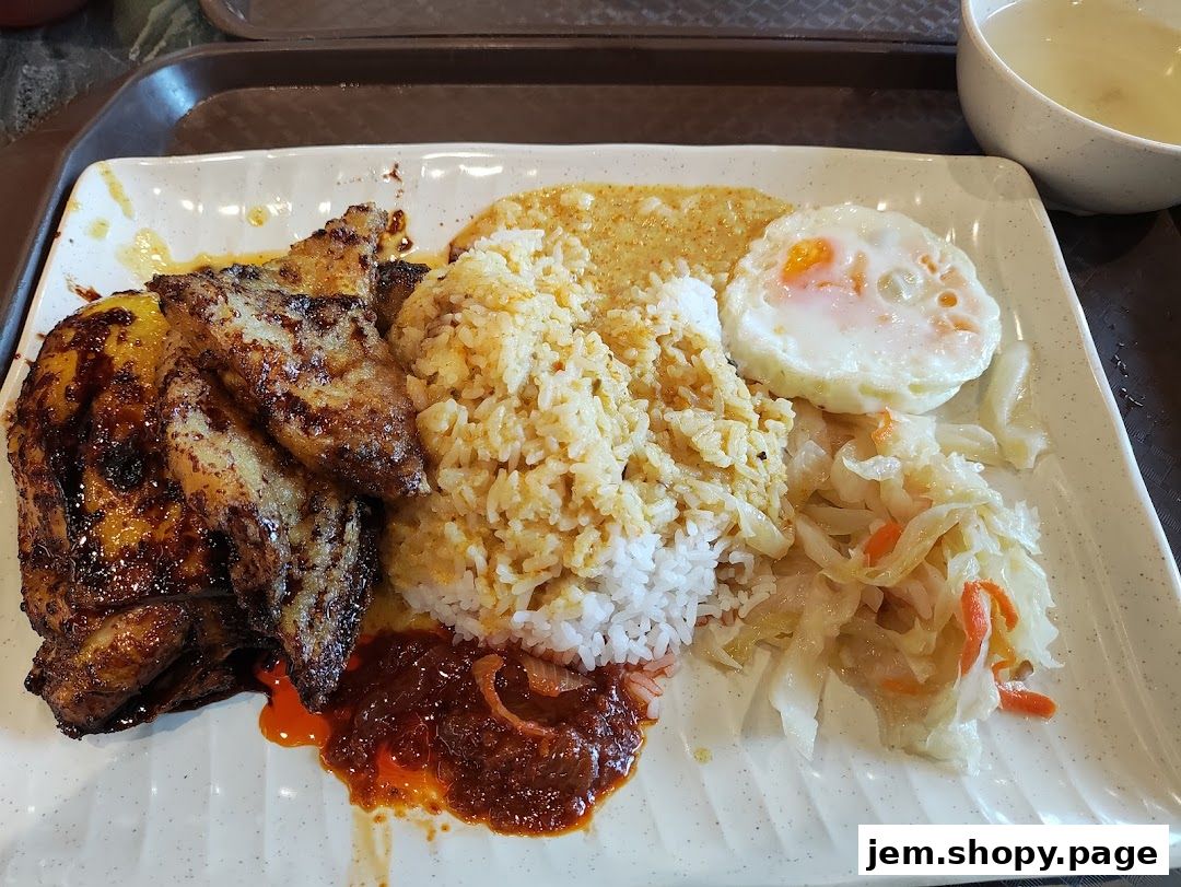 A plate of Indonesian BBQ chicken with rice, fried egg, and pickled vegetables.