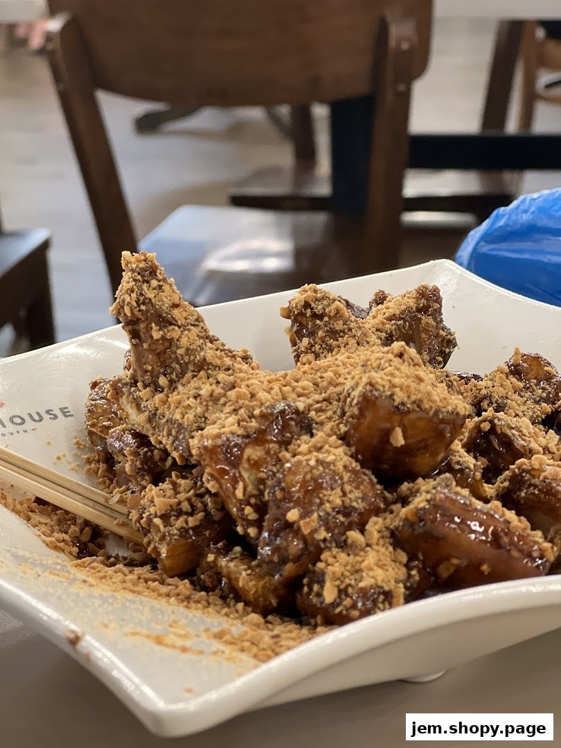 A close-up of a dish of fried food covered in sauce and crushed peanuts.