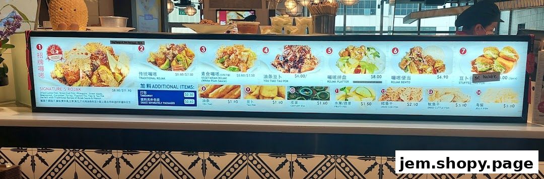 A brightly lit menu board displaying various Rojak dishes and additional items with prices.