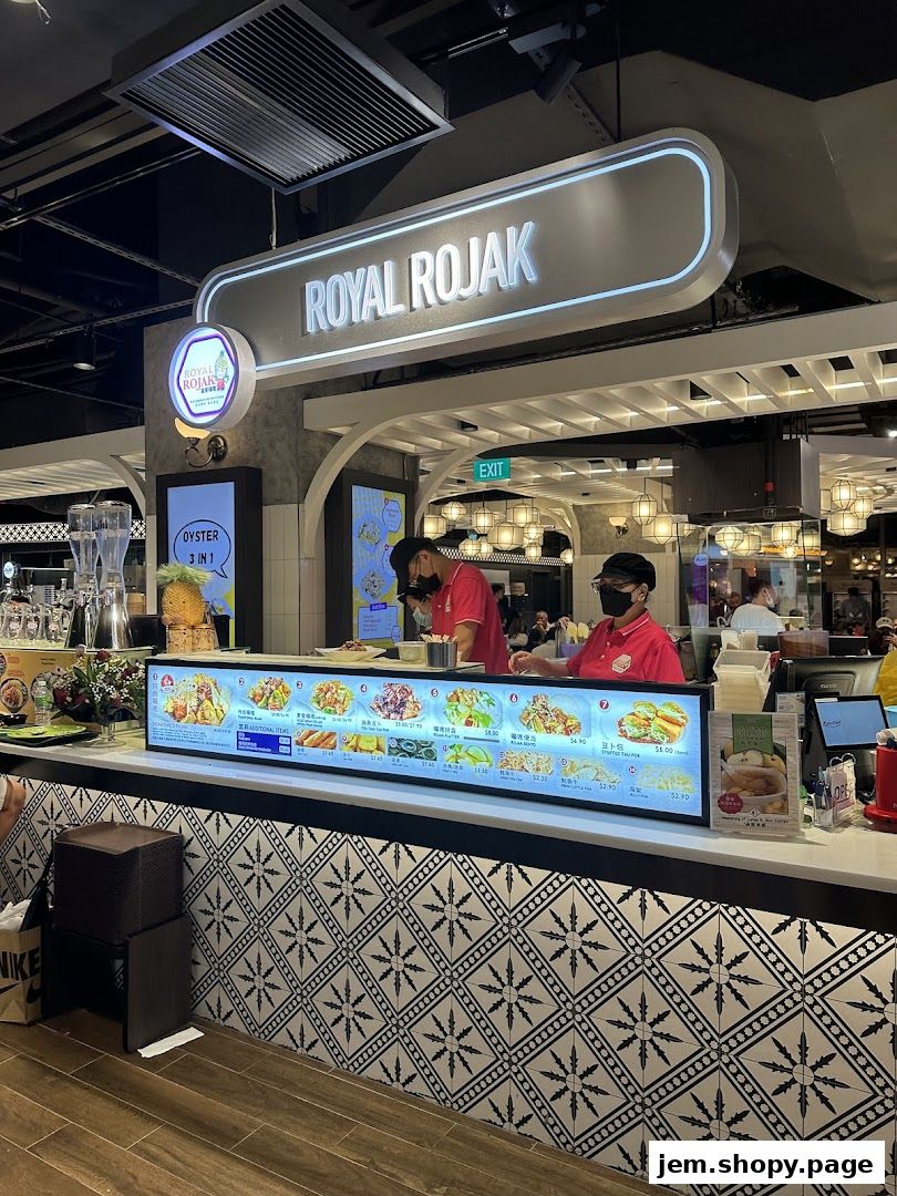 A food stall named Royal Rojak with a menu display and staff serving customers.