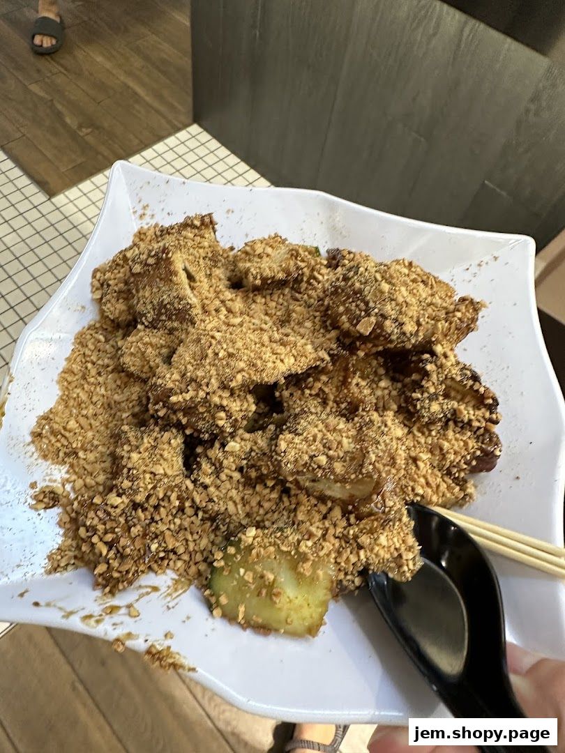 A plate of rojak topped with crushed peanuts and served with chopsticks and a spoon.