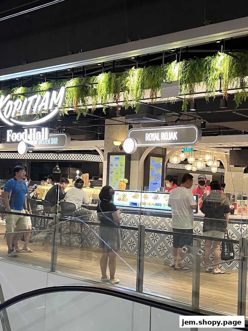 People queuing at a food stall in a food hall with hanging plants.