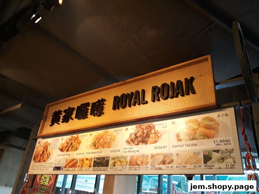 A food stall menu board displaying various Rojak dishes and side items with prices.