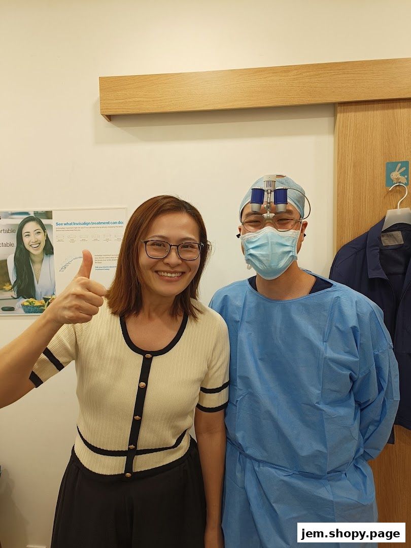 A smiling woman gives a thumbs-up next to a dentist in surgical attire.