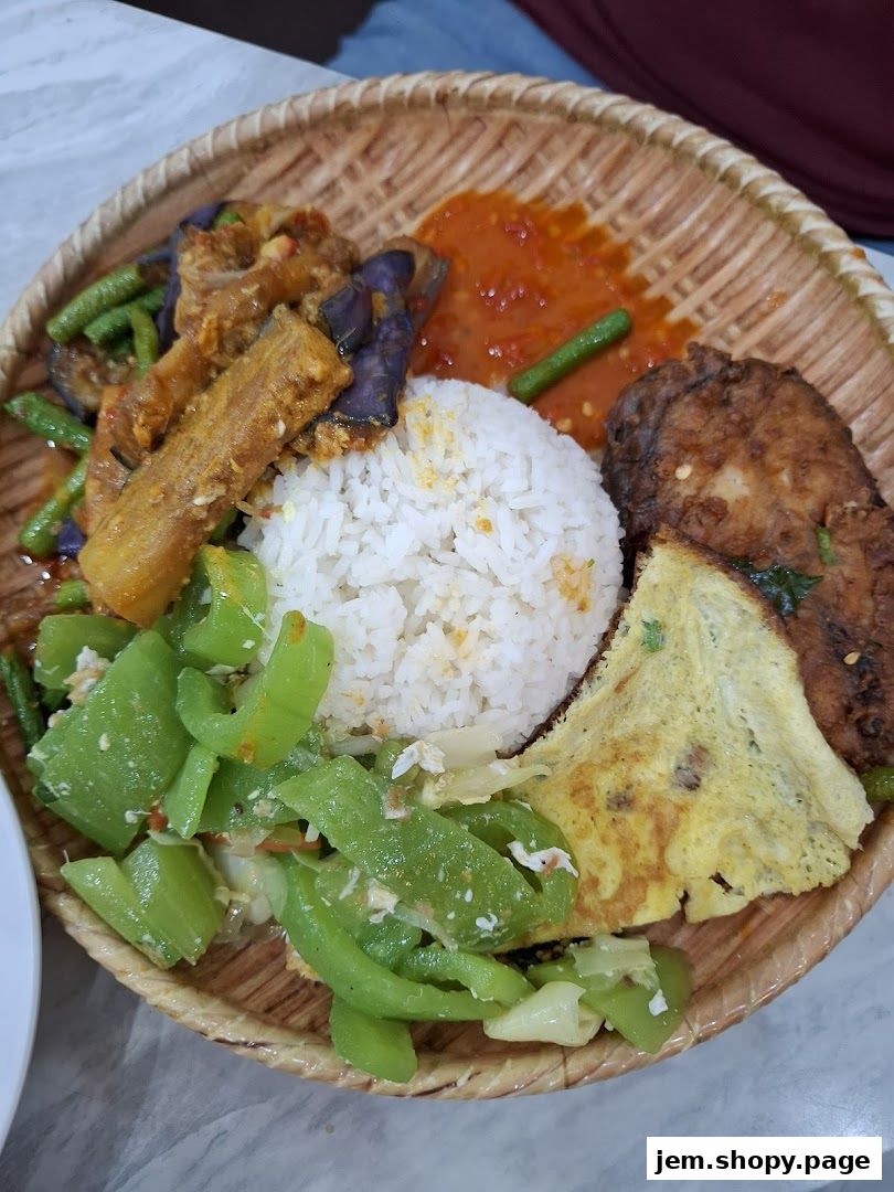 A woven platter filled with rice, fried fish, omelet, and various stir-fried vegetables.