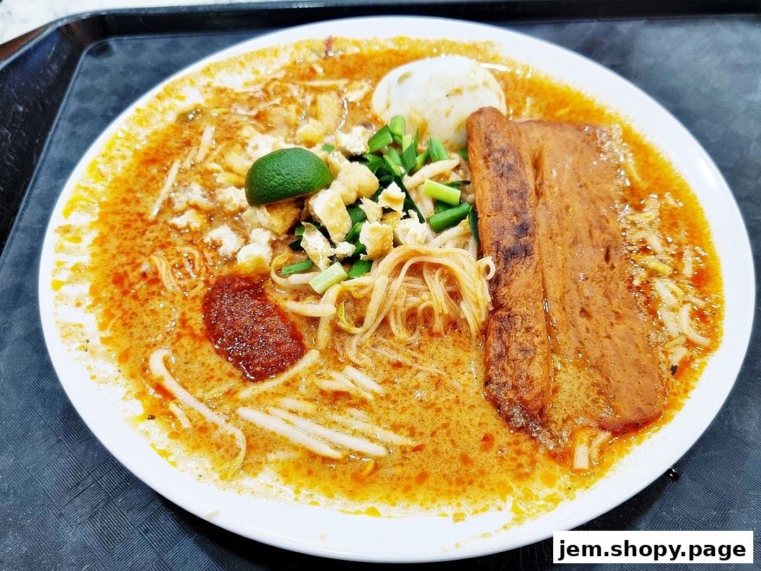 A close-up of a delicious bowl of curry noodles with egg, tofu, and chili paste.