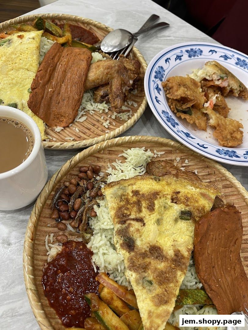 A close-up of two plates of nasi lemak with fried chicken, omelet, and sambal.