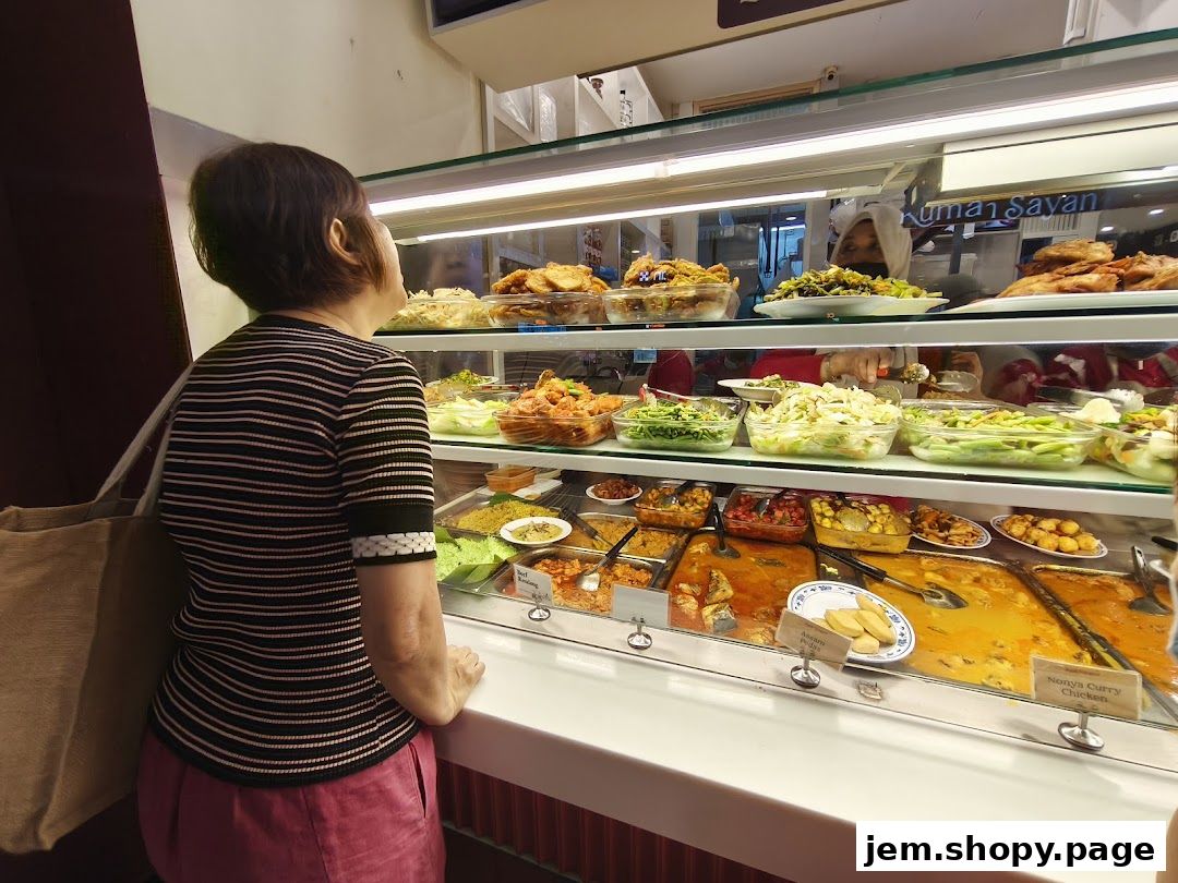 A woman looks at a display of various dishes at a food stall.