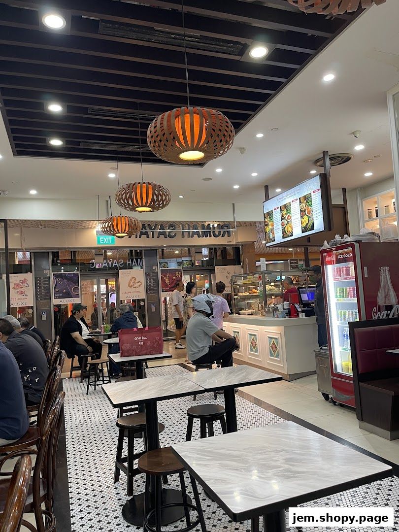 Interior view of Rumah Sayang restaurant with seating, counter, and display of food.