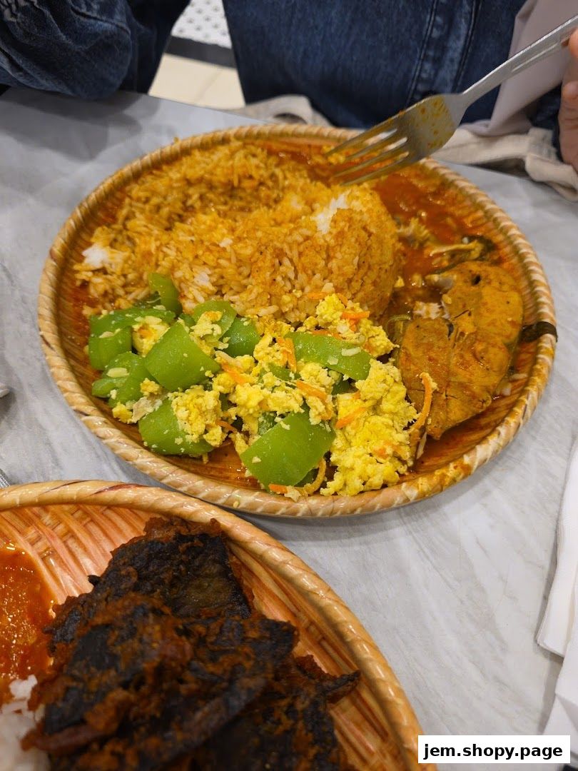 A close-up of two woven platters filled with rice, fish, scrambled eggs, and vegetables.
