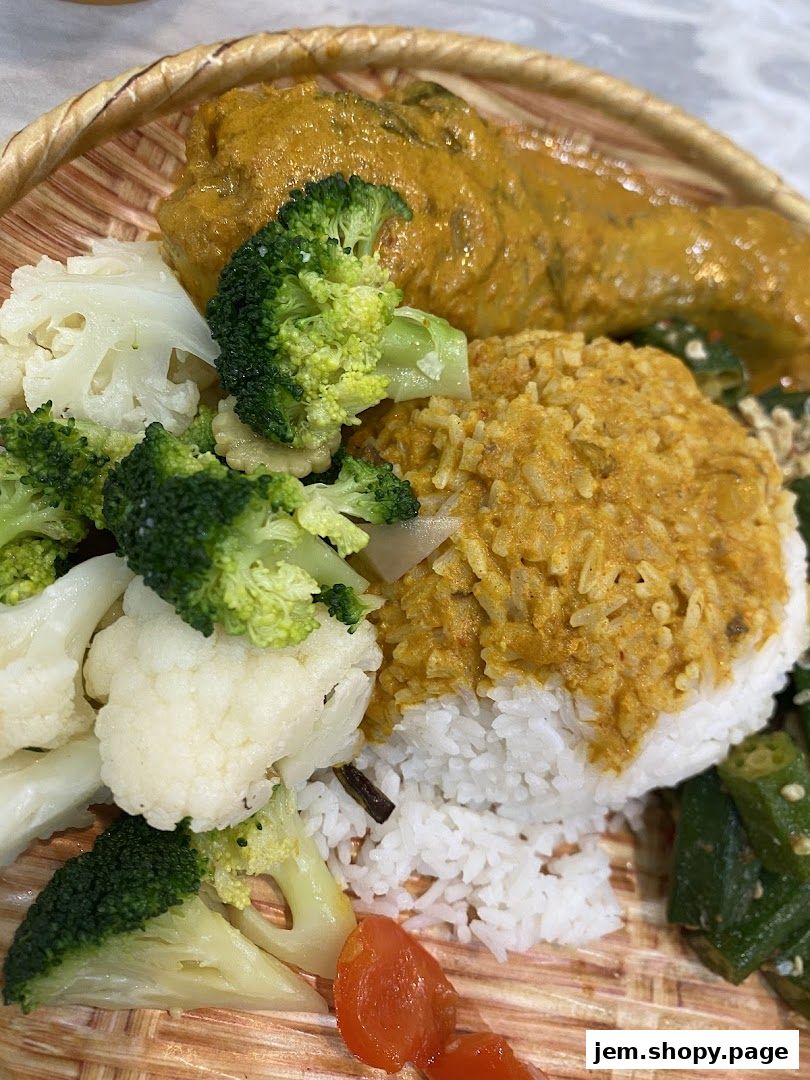 A close-up of a delicious meal featuring rice, curry chicken, and steamed vegetables.