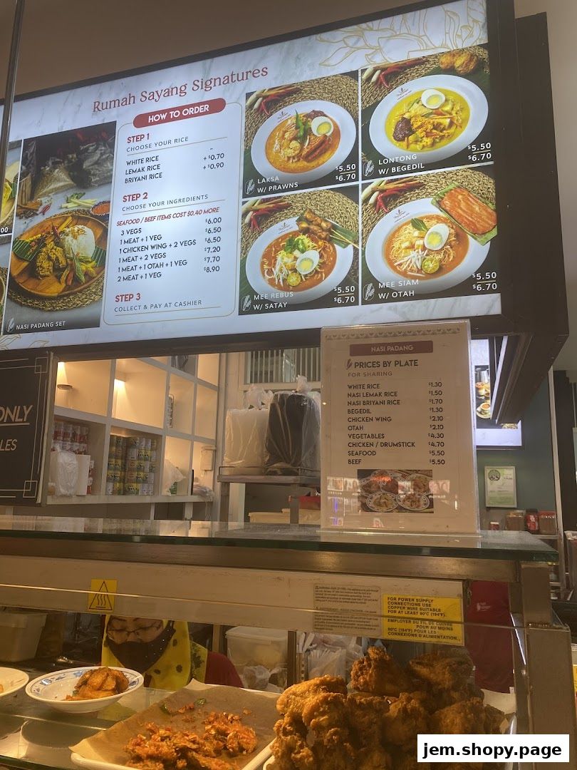 A menu board for Rumah Sayang featuring signature dishes like Laksa, Lontong, Mee Rebus, and Nasi Padang.