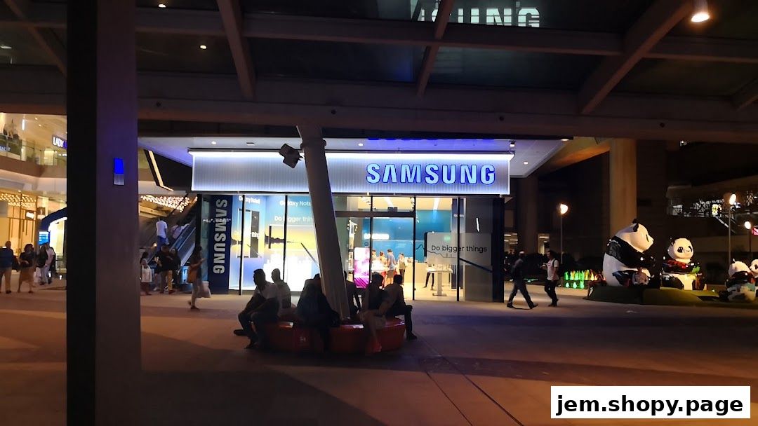 Samsung Service Centre Jem storefront at night with people outside.
