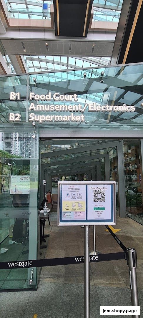 Entrance to a shopping mall with directional signs and a TraceTogether check-in station.