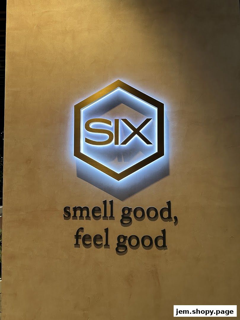 The Scent by SIX Jem shop logo and tagline are illuminated on a textured wall.