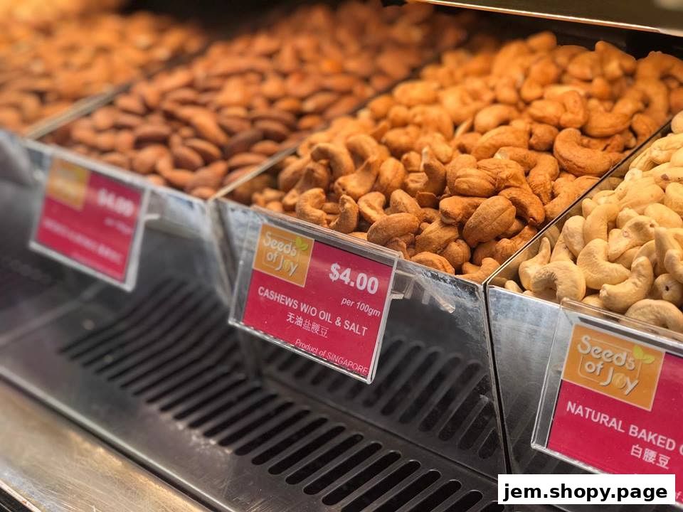 A display of various types of cashews with price tags at a shop called Seeds of Joy.