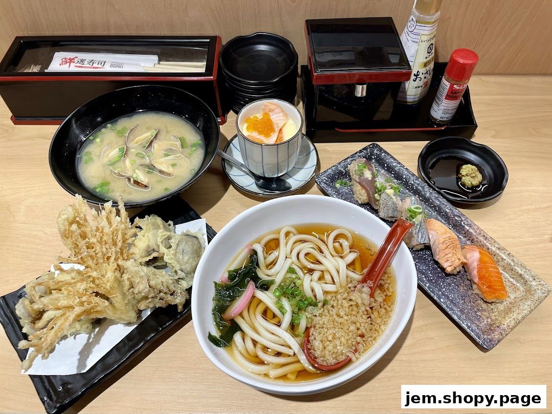 A spread of Japanese dishes including udon, tempura, sushi, chawanmushi, and miso soup.