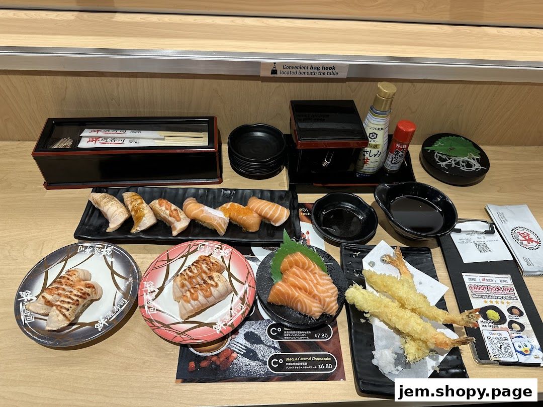 A variety of sushi, sashimi, and tempura are laid out on a wooden counter.