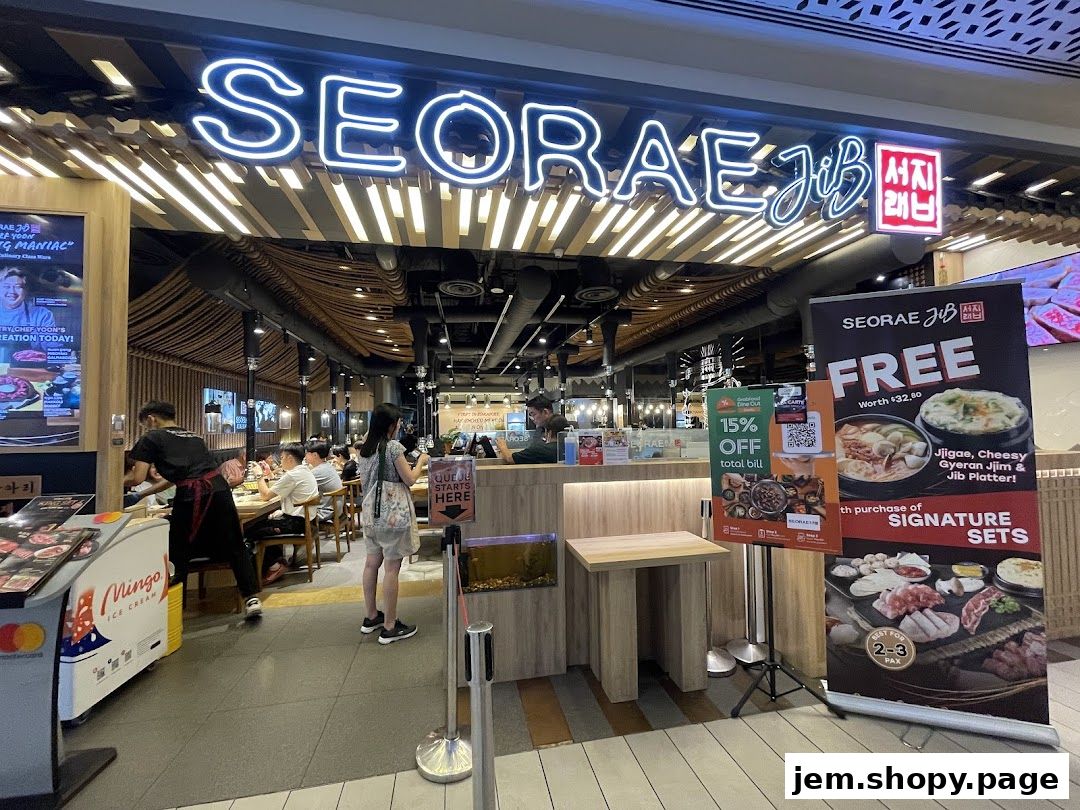 The exterior of a Korean BBQ restaurant, SEORAE JIB JEM, with promotional banners and customers inside.
