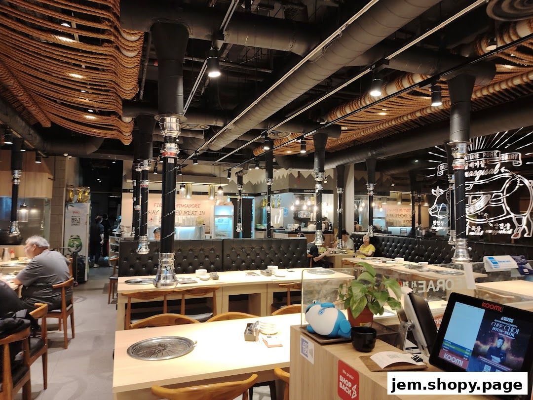 Interior of a Korean BBQ restaurant with tables, seating, and ventilation systems.