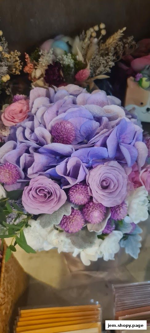 A beautiful arrangement of purple hydrangeas, roses, and other delicate flowers.