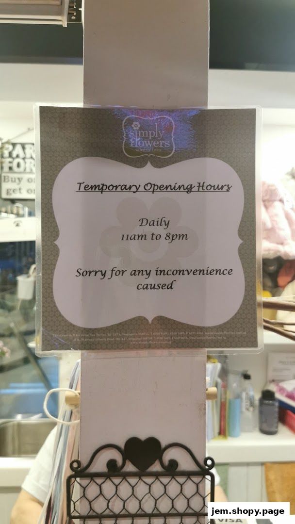 A sign displays temporary opening hours for Simply Flowers, open daily from 11 am to 8 pm.