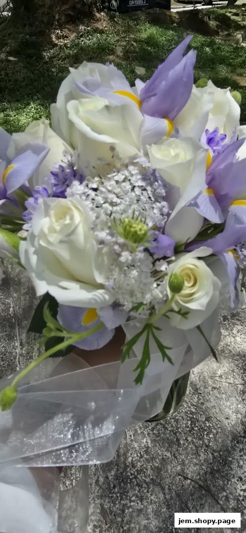 A beautiful bouquet of white roses and purple irises with delicate white filler flowers and ribbon.