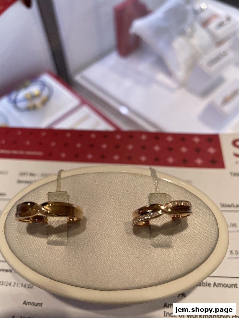 Close-up of two elegant gold rings displayed on a stand, with other jewelry visible in the background.