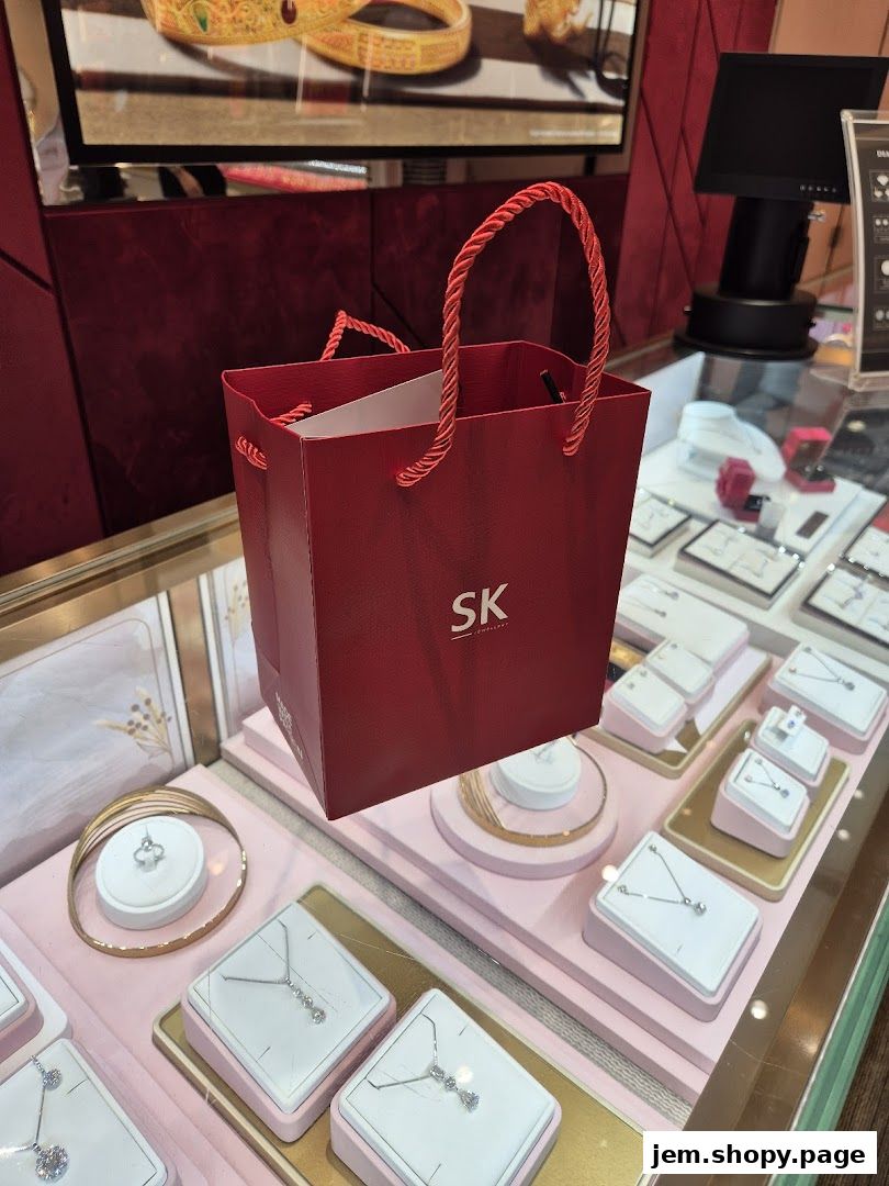 A red SK Jewellery shopping bag displayed over a jewelry display case.