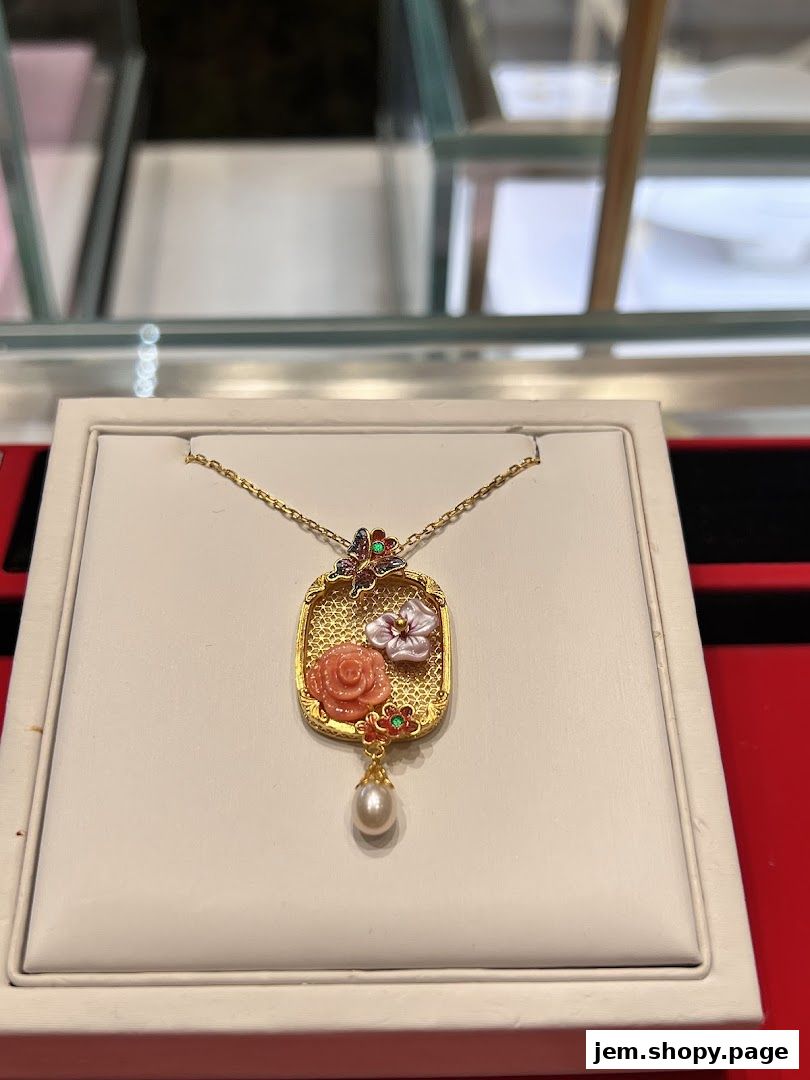 A close-up of a gold pendant with floral and butterfly designs, featuring a pearl.