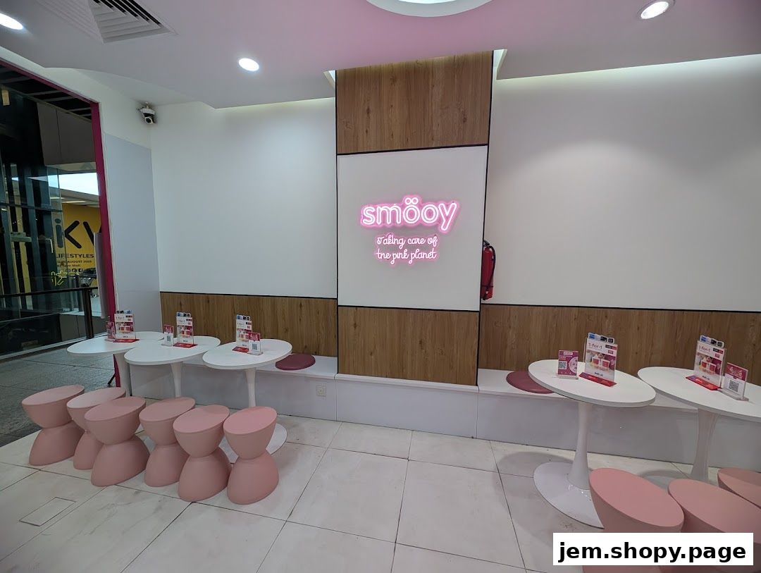 Interior of a smöoy shop with pink stools, white tables, and neon signage.