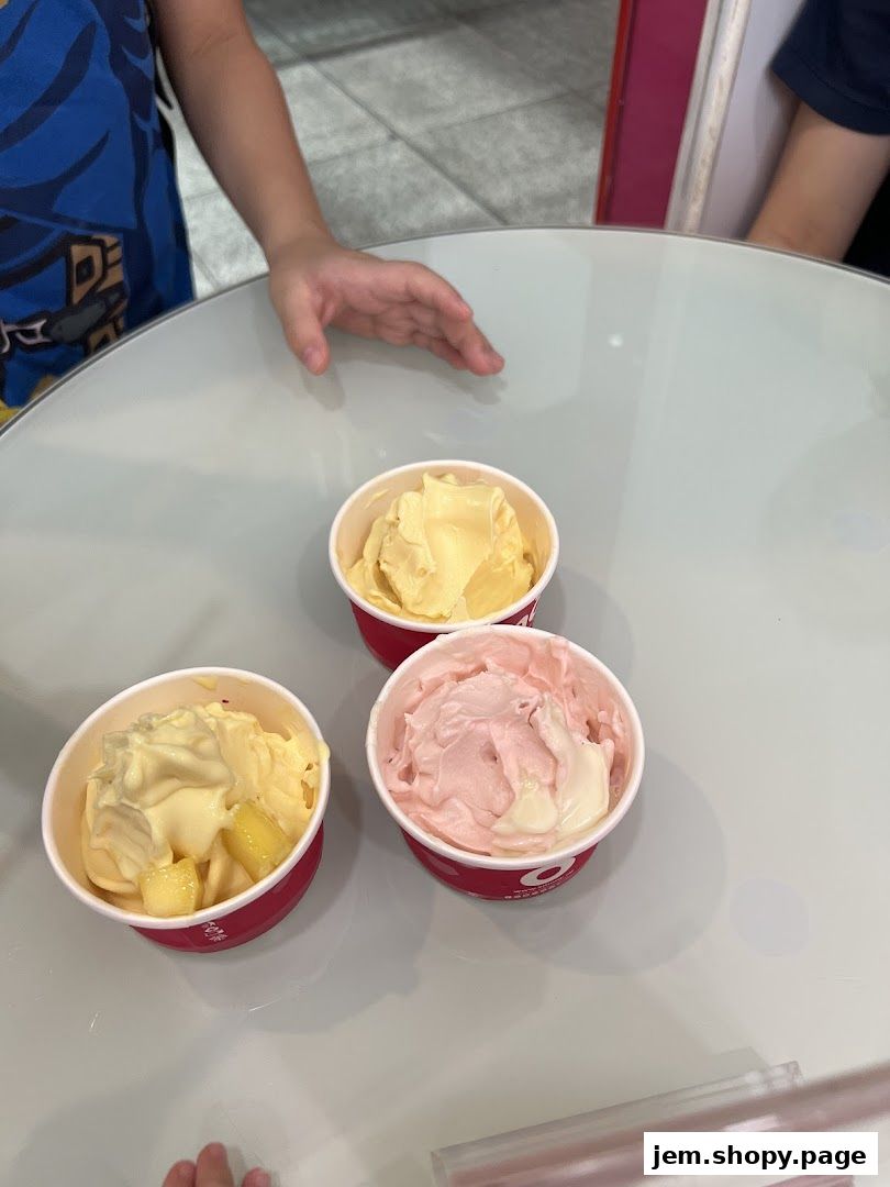 Three cups of frozen yogurt with different flavors and toppings on a table.