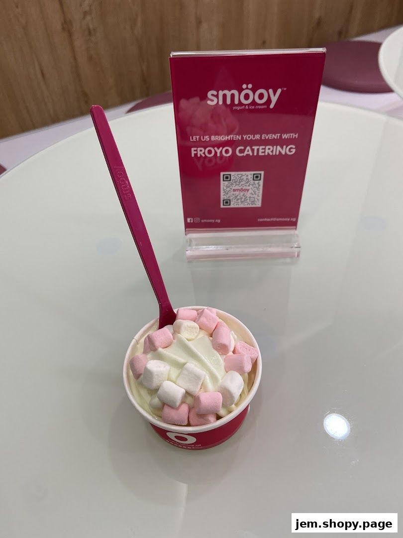 A cup of froyo with marshmallows and a pink spoon, with a sign promoting froyo catering.