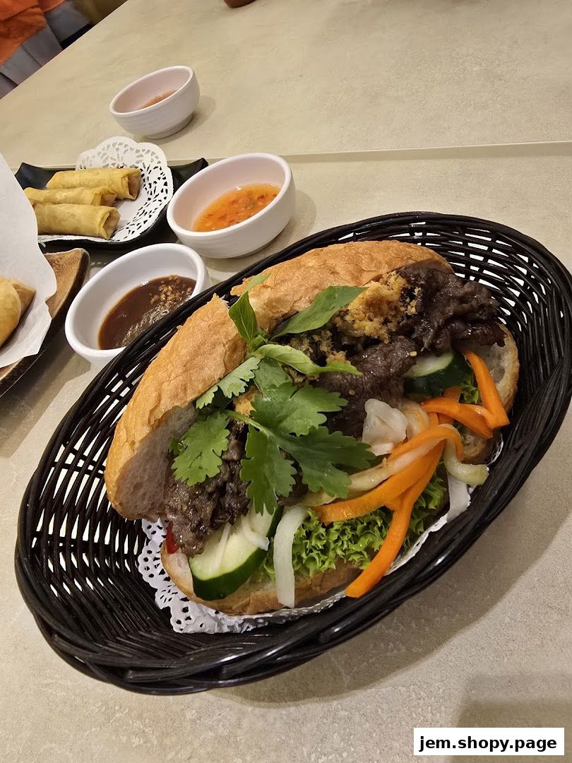 A delicious Banh Mi sandwich with spring rolls and dipping sauces on a table.