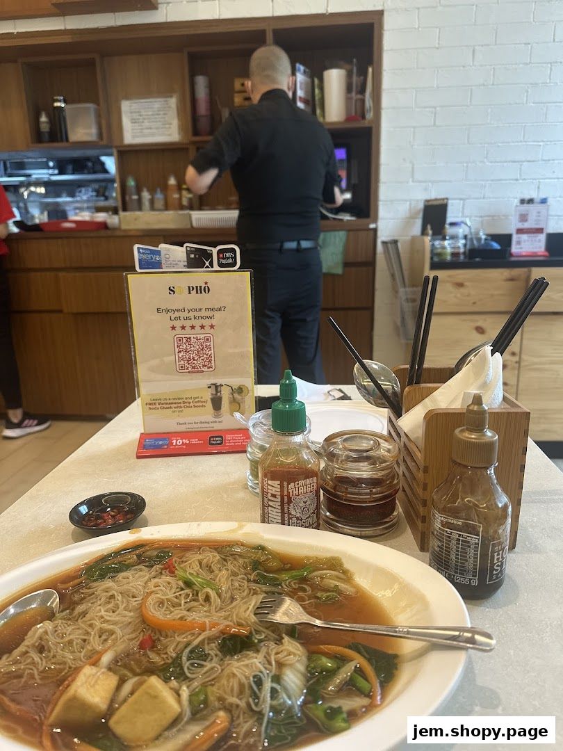 A table setting at So Pho restaurant with a bowl of noodles and condiments.