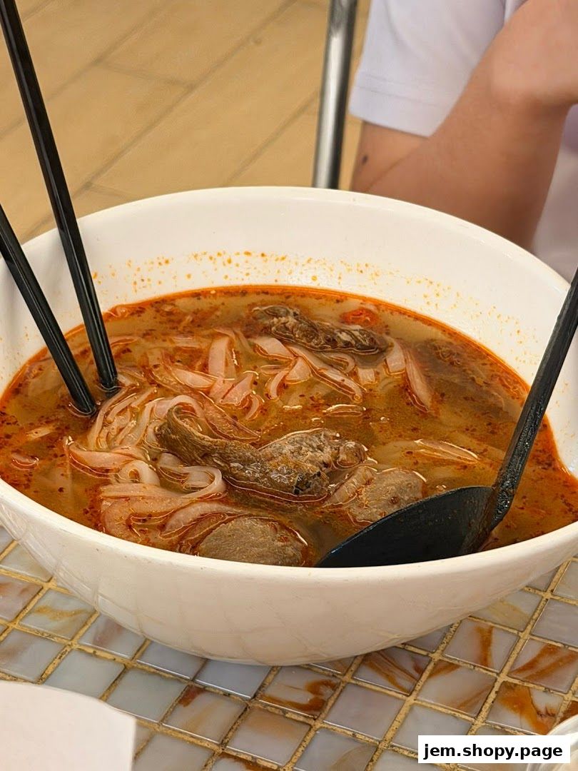 A close-up of a steaming bowl of pho with noodles, meat, and broth.