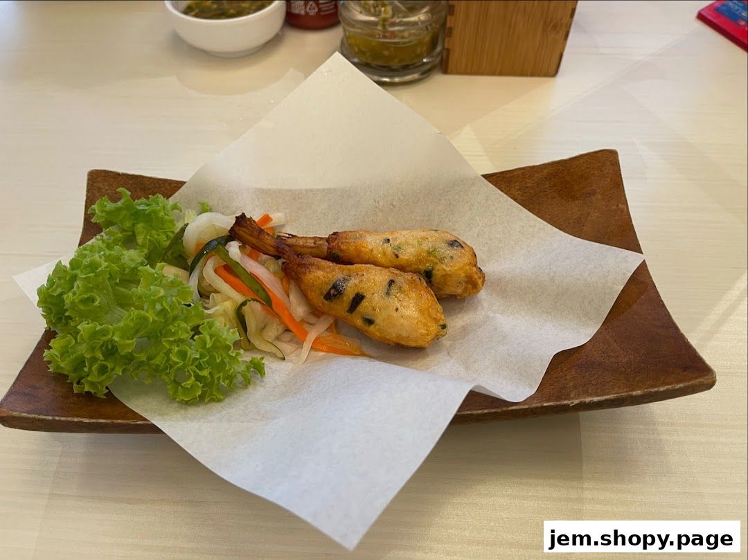 Two fried shrimp cakes served with lettuce and pickled vegetables on a wooden plate.