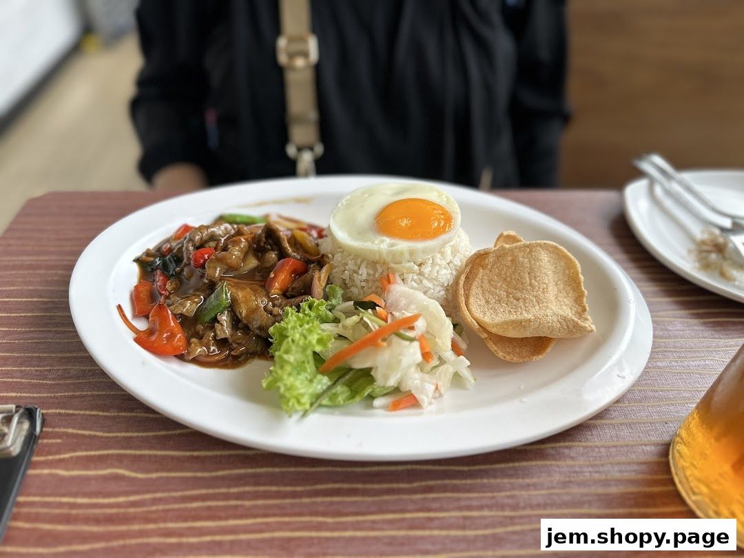 A plate of Vietnamese food with rice, stir-fried meat, vegetables, and a fried egg.