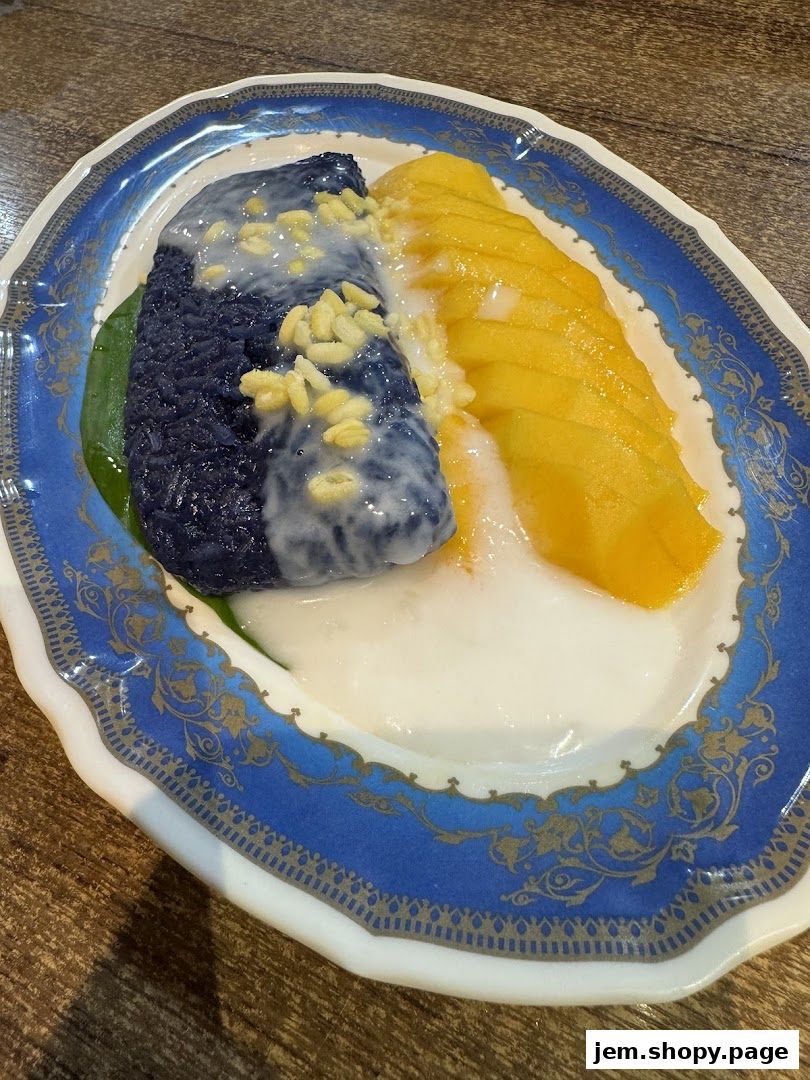A close-up of a Thai dessert with mango and sticky rice on a decorative plate.