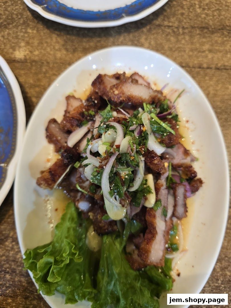 A plate of delicious Thai grilled pork salad with fresh vegetables and herbs.