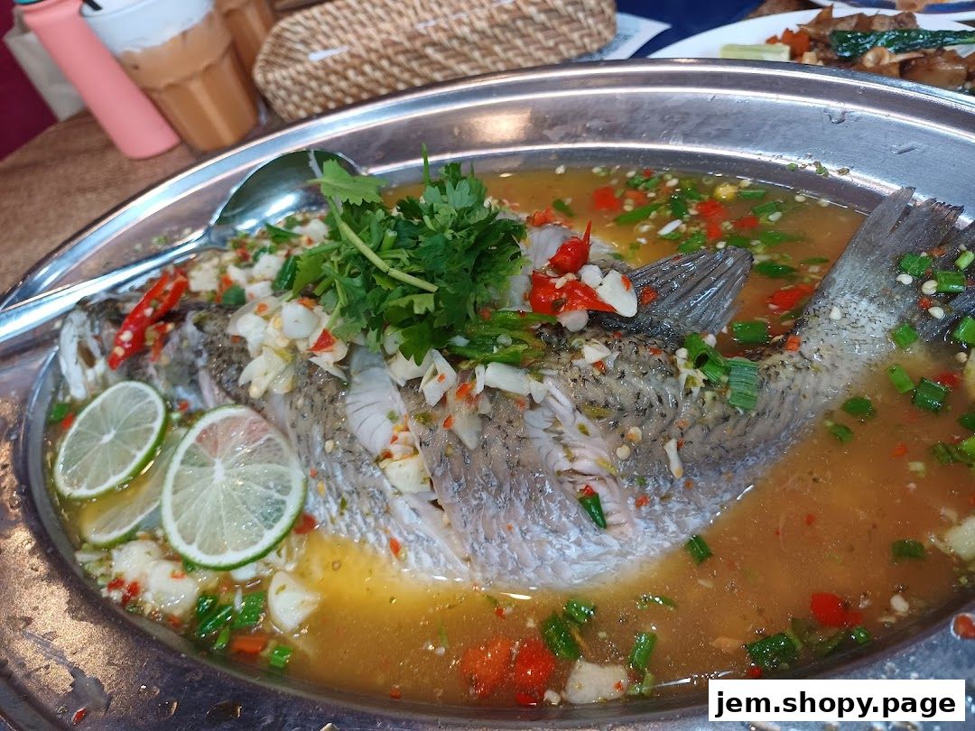 A whole steamed fish dish with lime, chili, and herbs in a savory broth.