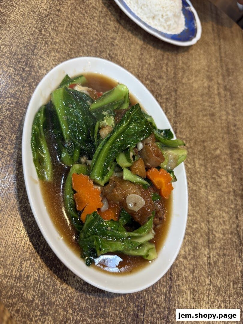 A plate of stir-fried vegetables with meat in a savory sauce, served with rice.