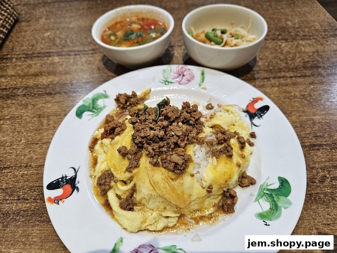A plate of Thai minced meat with omelette and rice, served with two small bowls of soup.